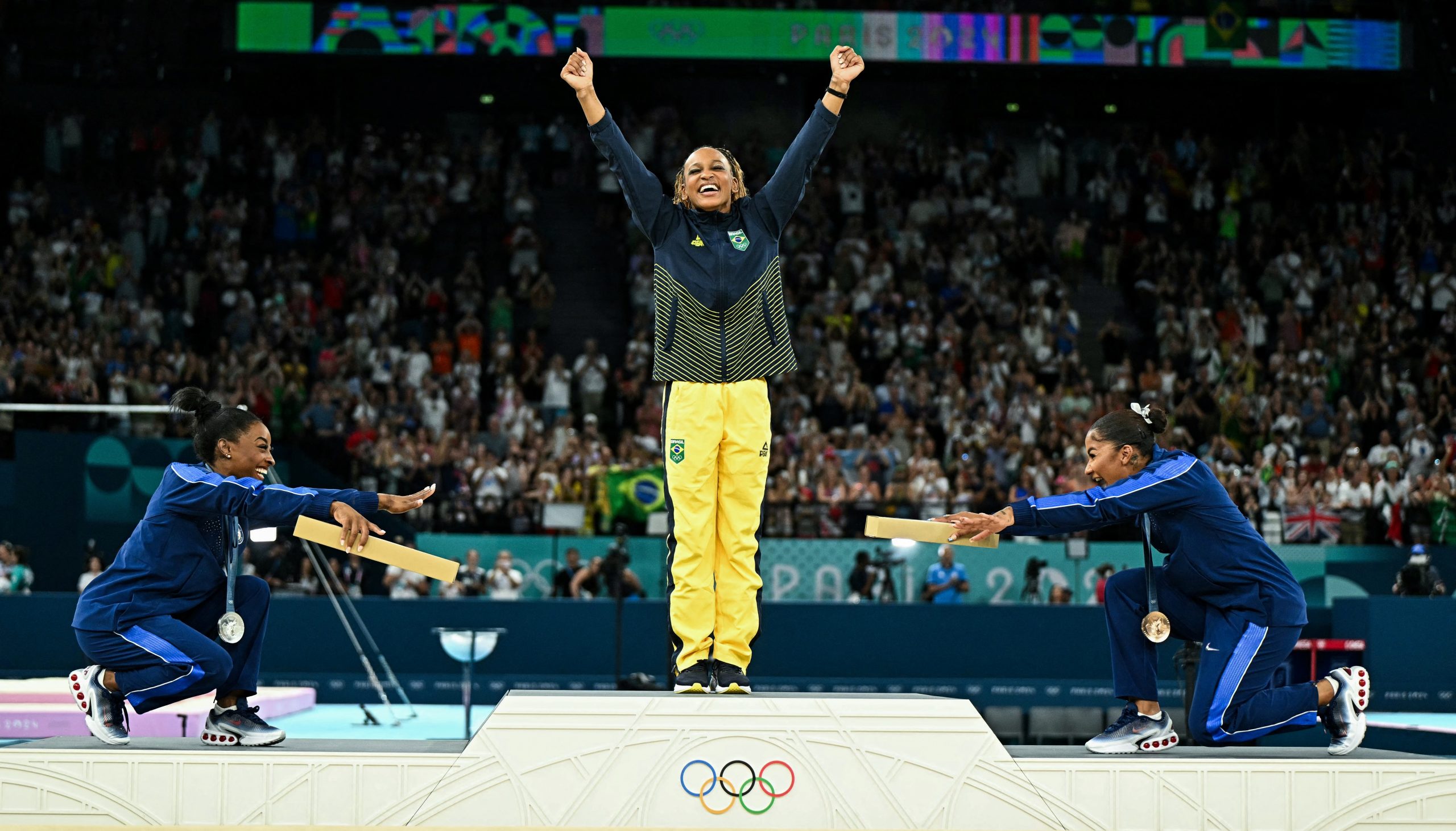 A reverência sorridente de Simone Biles e Jordan Chiles à campeã Rebeca Andrade: uma das grandes imagens olímpicas de todos os tempos. Foto Gabriel Bouys/AFP