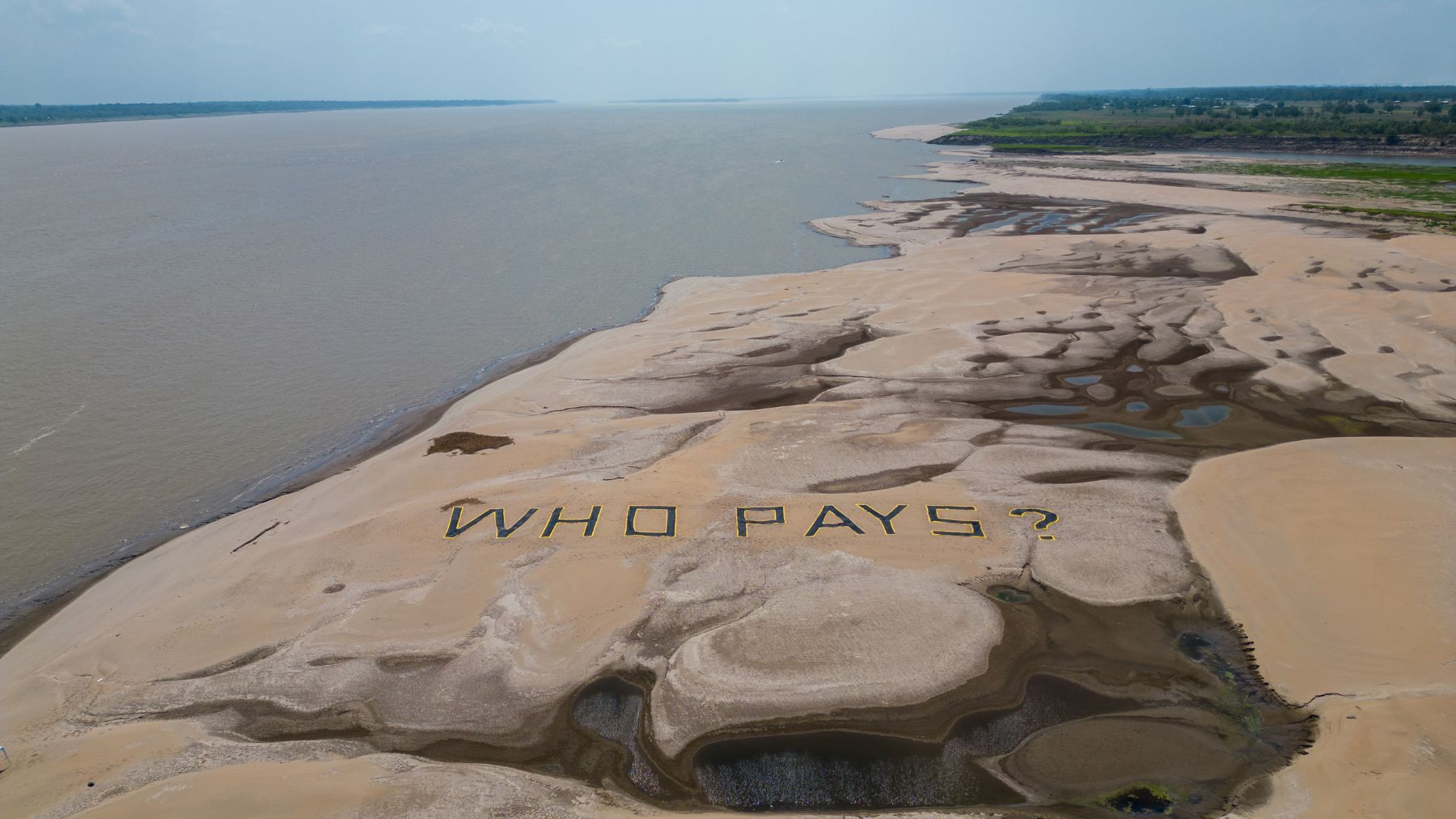 "Quem paga?" pergunta, em inglês, a ação do Greenpeace no Solimões seco: estiagem extrema afeta ribeirinhos e povos indígenas na Amazônia (Foto: Nilmar Lage / Greenpeace)