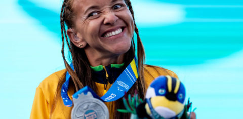 Foto colorida da atleta paralímpica Samira Brito. Ela é uma mulher negra com cabelo dreads. Ela segura sua medalha de prata no Parapan de Santiago 2023, enquanto sorri