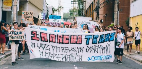 Foto colorida de estudantes segurando faixa durante marcha da consciência trans em Campinas. Movimento foi idealizado para buscar cotas para pessoas trans na Universidade