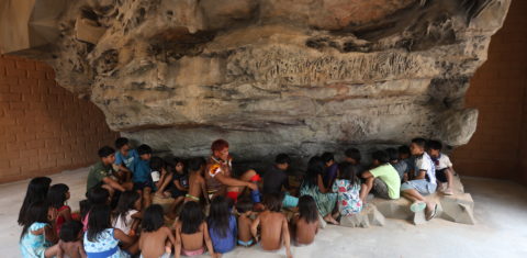 Crianças aprendendo sobre a história do guerreiro Kamukuwaká com a réplica da gruta em 3D instalada no Centro Cultural e de Monitoramento Territorial da aldeia Ulupuwene. (Alaor Filho/ Fotos Públicas)