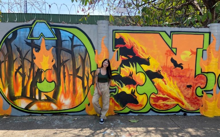 Nath, uma das autoras, à frente do mural denunciando desmatamento e seca na Amazônia: arte contra o caos climático (Foto: Rainer Almeida)