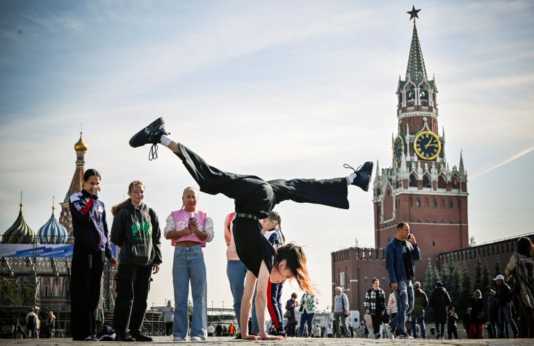 Ginasta russa posa para uma foto na Praça Vermelha, em frente ao Kremlin e à Catedral de São Basílio, no centro de Moscou. País enfrenta "inverno demográfico" com boas possibilidades de crescimento. Foto Alexander NEMENOV/AFP. Setembro/2024