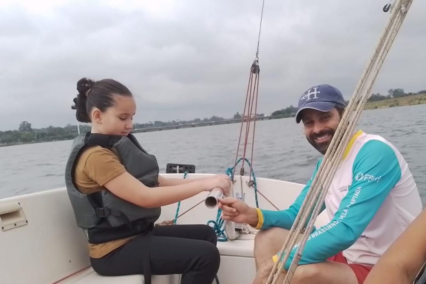 Ana Clara, 9 anos, cega de nascimento e seu instrutor: modo peculiar de 'ver' ao velejar proporcionado pelo projeto Vela Adaptada (Foto: Divulgação)