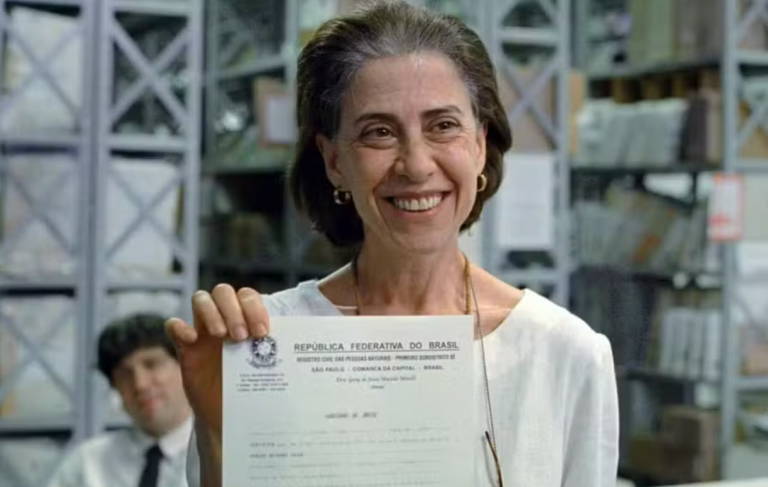 Fernanda Torres, em Ainda Estou Aqui, repete a cena em que Eunice mostra sorridente a certidão de óbito de Rubens Paiva: retificação para incluir que desaparecidos foram vítimas de ação violenta do Estado (Foto: Divulgação)