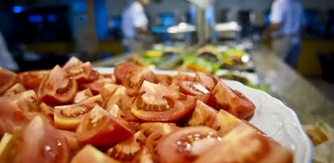 Foto colorida de mesa com tomate e outros alimentos ao fundo