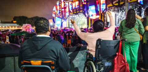 Foto colorida de pessoas usuárias de cadeira de rodas em área PcD do Festival Verão Massayó, em Maceió (AL)