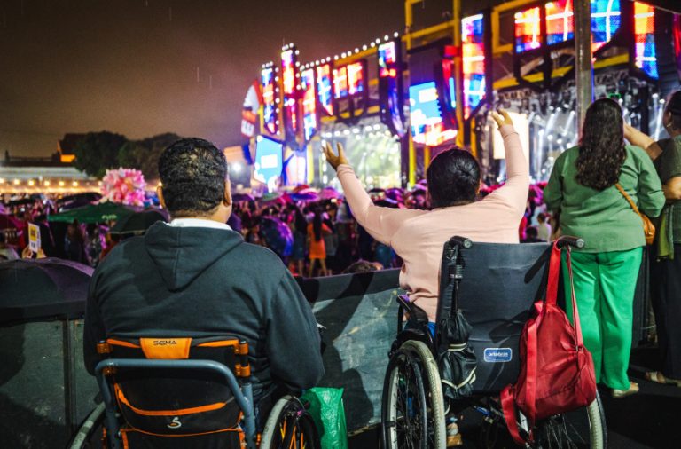 Foto colorida de pessoas usuárias de cadeira de rodas em área PcD do Festival Verão Massayó, em Maceió (AL)