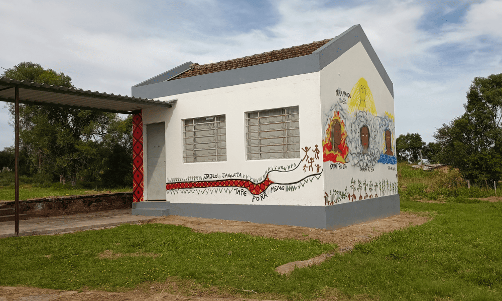 Foto colorida de uma das salas da escola Yvyra Ijá Tenondé Vera Miri, com pinturas feita pelos estudantes de elementos da cultura Guarani