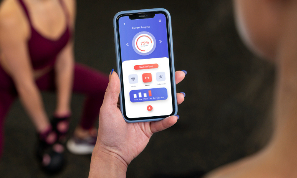 Foto colorida que mostra mulher olhando aplicativo de monitoramento de exercícios, como o GymRats