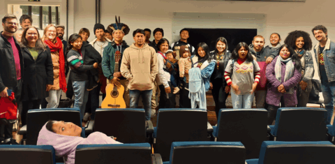 Foto colorida de estudantes Mbyá-Guarani e o público no auditório do prédio 40A da UFSM, em Santa Maria. Na imagem, as pessoas aparecem em grupo posando para a foto.