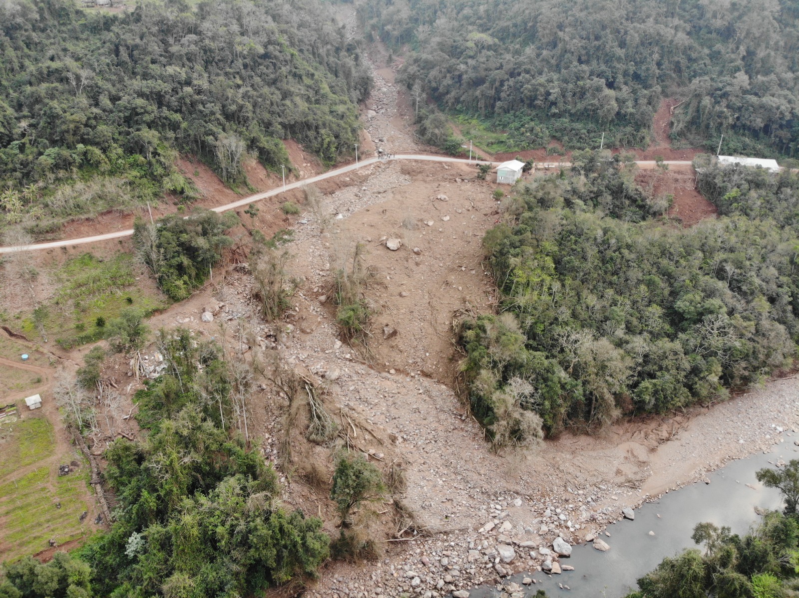 Foto colorida de deslizamento de terra após chuvas no Rio Grande do Sul. Na imagem de satélite, aparece o curso do deslizamento que passa por uma estrada