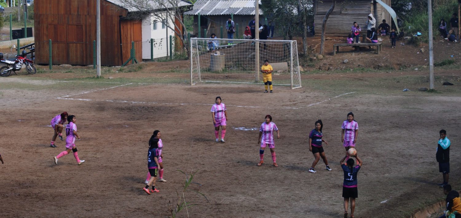Foto colorida de partida da Liga Mbya Gurani de futebol 7 na Tekoá Itaty, na Terra Indígena Morro dos Cavalos. Na imagem, aparecem jogadoras do Kunhangue Itaty e do Barra Funda FC