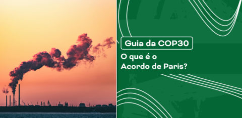 Chaminés industriais liberando fumaça contra um céu alaranjado, simbolizando emissões de gases do efeito estufa - principal tema das metas climáticas do Acordo de Paris.