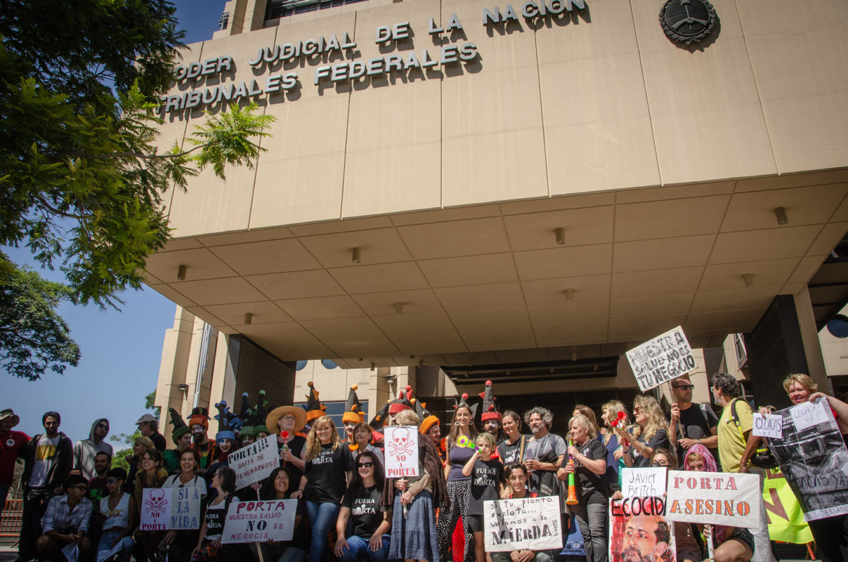 Foto colorida com manifestantes do movimento Fuera Porta em frente a prédio do poder judiciário argentino.