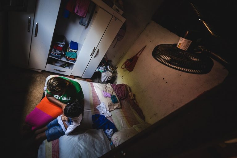 Jéssica Lima com o filho Kássio em casa num dia de calor extremo em Maceió: pobreza agrava os riscos das altas temperaturas para pacientes com transtorno de saúde mental (Foto: Jonathan Lins)