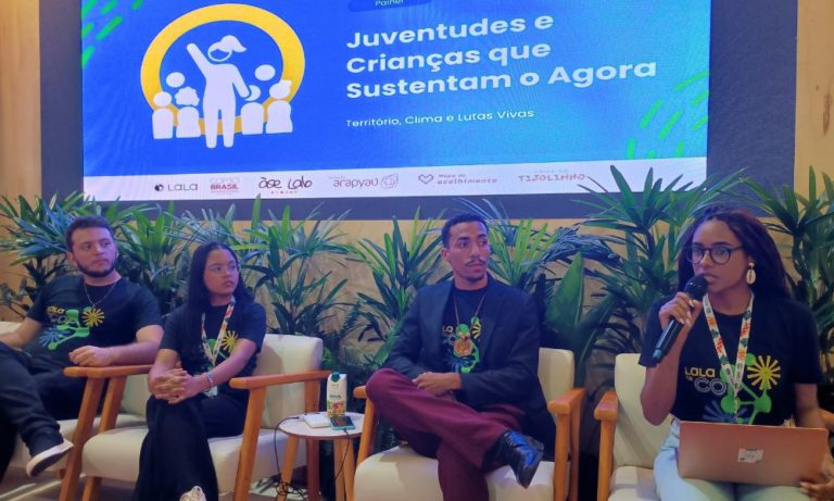 Foto colorida do painel: “Juventudes e crianças que sustentam o agora: território, clima e lutas vivas”. Na imagem, da esquerda para a direita, aparecem Marcelo, Fabrina e Vinícius e a mediadora Marta Melo