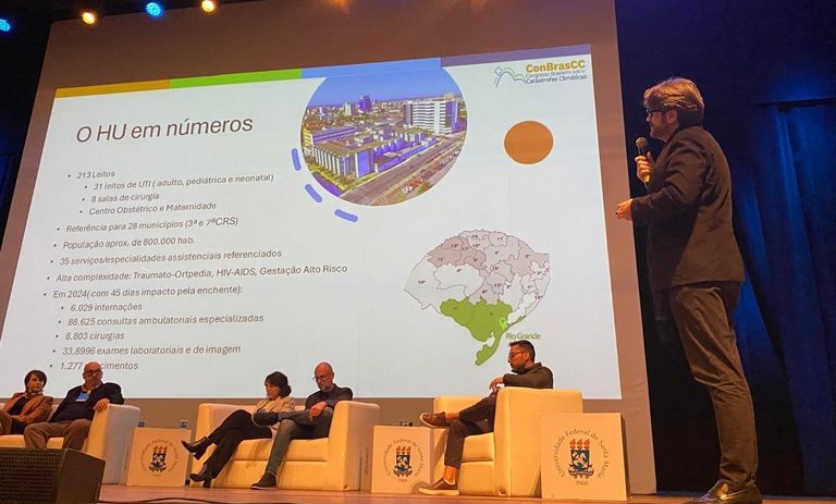 Foto colorida de Fábio Lopes em apresentação durante o Congresso Brasileiro sobre Catástrofes Climáticas na UFSM.