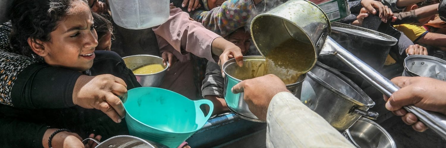 Foto colorida de pessoas com panelas, durante distribuição de alimentos na Faixa de Gaza em maio de 2025; insegurança alimentar cresce pelo mundo