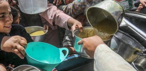 Foto colorida de pessoas com panelas, durante distribuição de alimentos na Faixa de Gaza em maio de 2025; insegurança alimentar cresce pelo mundo