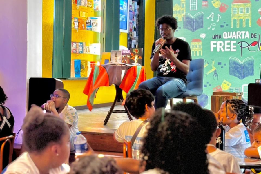 Foto colorida de Anderson Shon falando sobre as obras Estados Unidos da África e do O Sítio da Tia Naná com crianças do Pelourinho, em Salvador