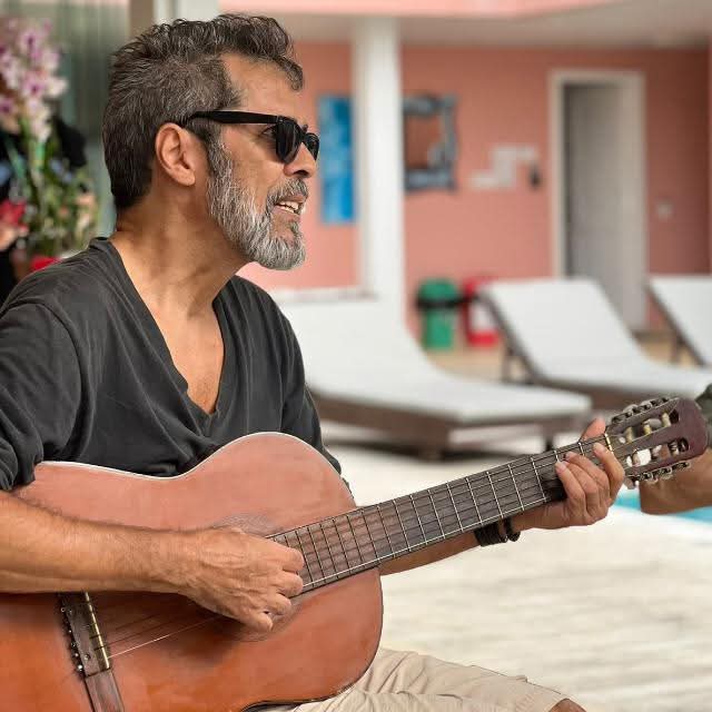 Foto colorida de Claudio Duarte segurando violão