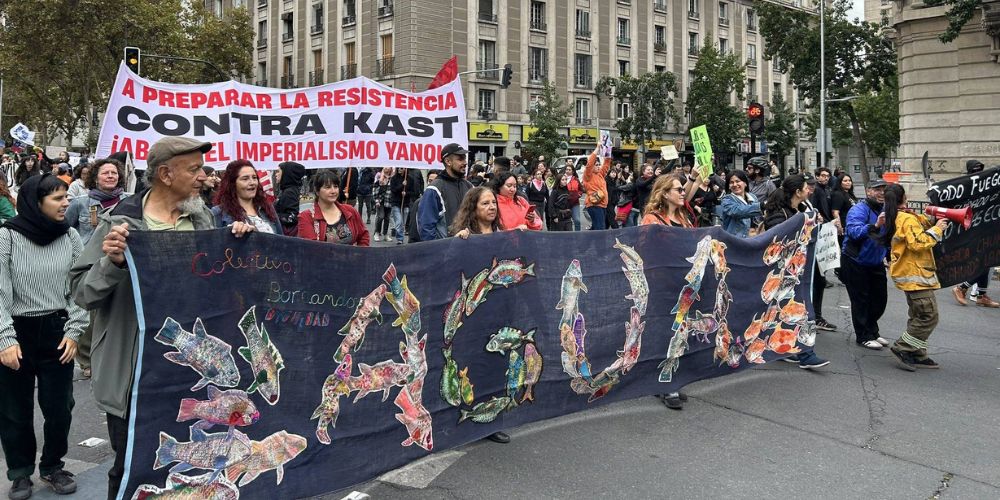 Foto colorida de pessoas em manifestações contra revogação de decretos ambientais no Chile. Em primeiro plano, pessoas seguram faixa escrito "Água"