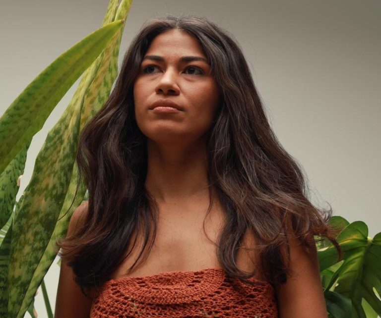 Foto colotida de Maiara Astarte. Ela tem cabelo preto, logo e liso, pele morena e olha para a frente