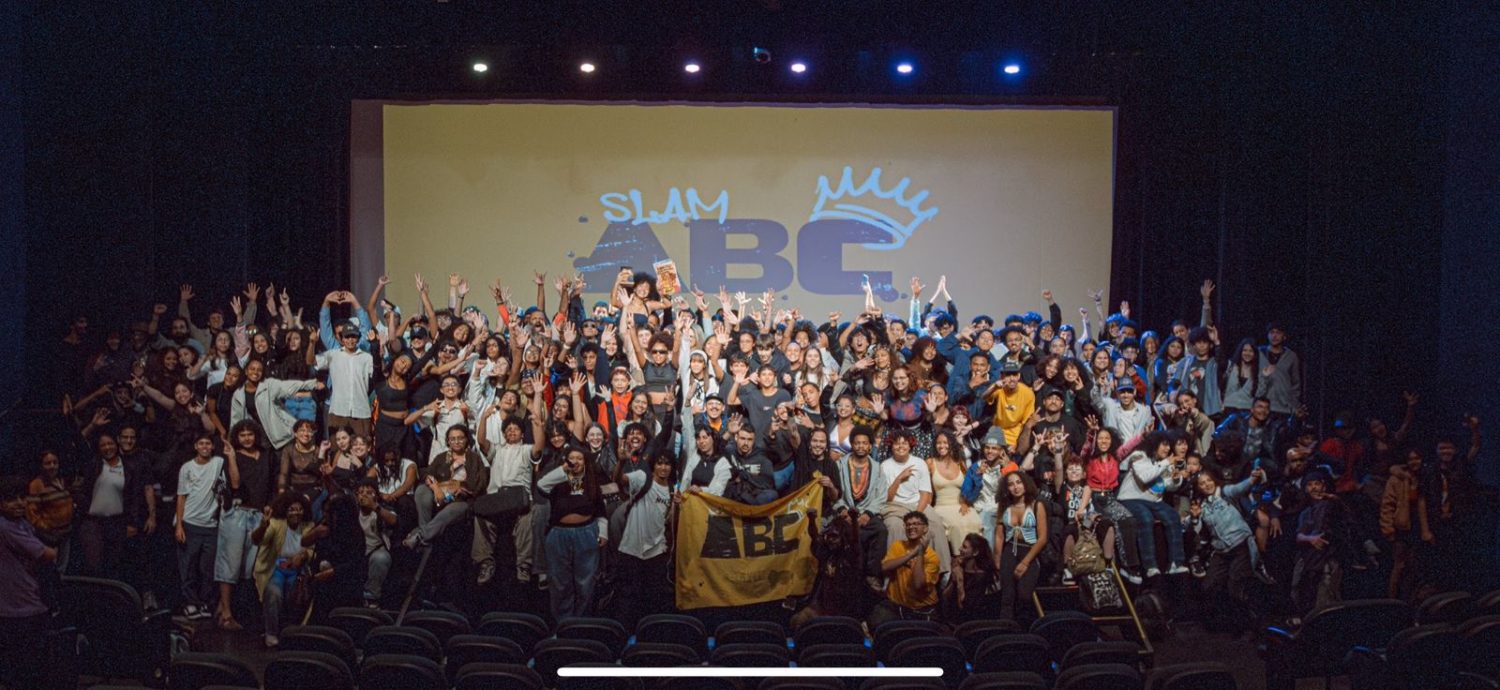 Foto colorida que mostra palco do Slam ABC com várias pessoas