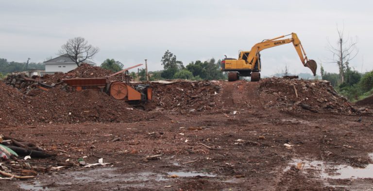 Foto colorida de terreno onde ficavam casas destruídas pelas enchentes em Arroio do Meio. No canto superior direito, aparece uma máquina trabalhando na remoção de escombros