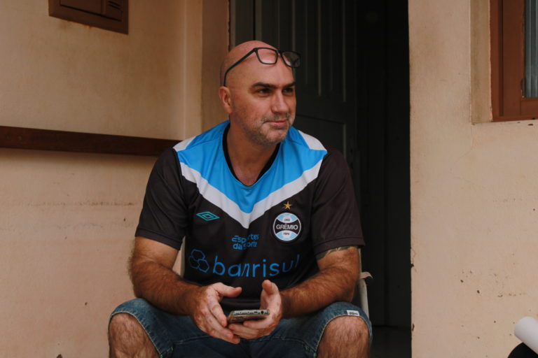 Foto colorida de Ivan Schauren. Ele é um homem branco, careca e com barba grisalha e está usando uma camiseta do Grêmio