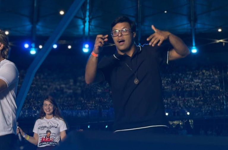Foto colorida de Gabriel Camargos fazendo tradução em Libras, durante show noturno no Estádio Mineirão
