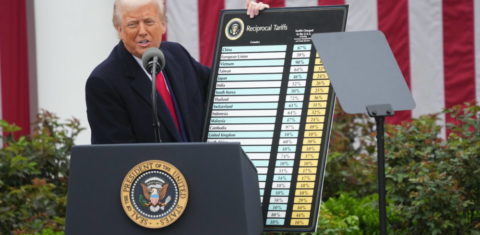 Foto colorida do presidente dos Estados Unidos, Donald Trump, segurando um placa com a lista de tarifas para diferentes países.