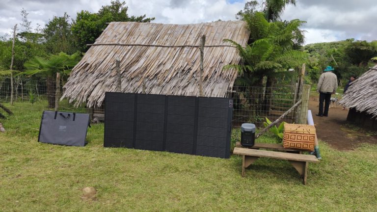 Foto colorida que mostra sistema fotovoltaico instalado na Teko’a Yvyty Porã, em Maquiné. Na imagem, aparecem os aparelhos e uma casa com telhado de palha ao fundo