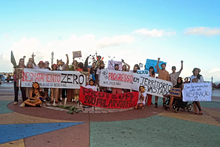 Foto colorida de várias pessoas reunidas com faixas em protesto contra o possível desmatamento de área da APA Aldeia-Beberibe para construção da escola de sargentos, em Pernambuco