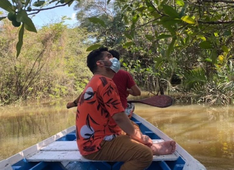 Foto colorida de Marcos em canoa, usando máscara.