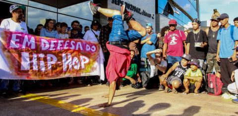 Foto colorida de jovem fazendo acrobacia durante marcha da Cultura Hip Hop, em Brasília