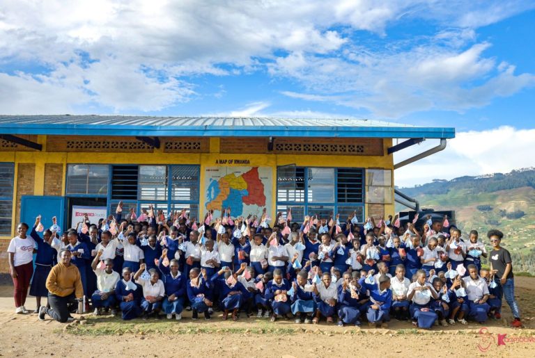 Blandine (à direita) com estudantes de escola em Ruanda e absorventes distribuídos pela Kosmotive: enfrentamento da pobreza menstrual (Foto: Divulgação)