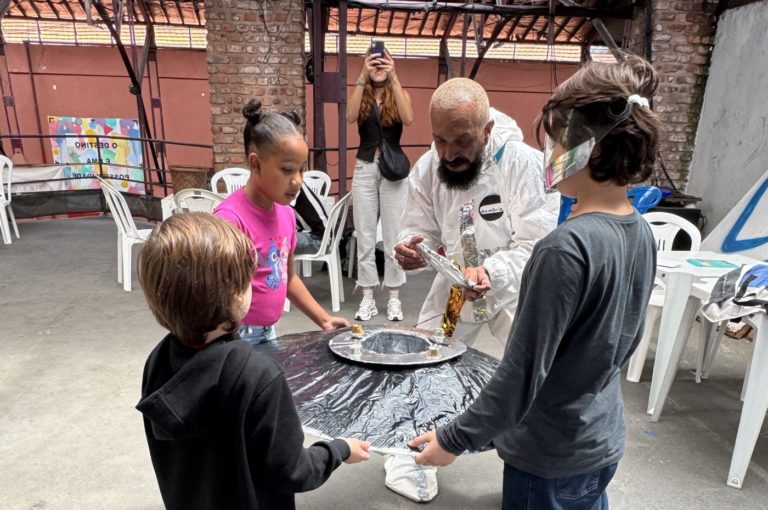 O 'astronauta' Rona Naves e crianças com a Nave Memória: oficina convida meninos e meninas a trabalharem as percepções sobre o futuro, por meio de cartas e desenhos (Foto: Sofia Ricardo)