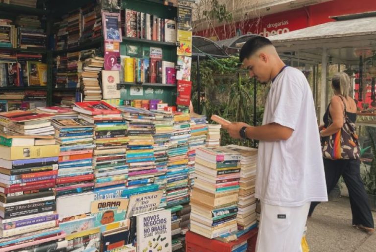 Cliente folheia livro no Sebo Rua das Flores na Tijuca: livraria na calçada é a única aberta 24h por dia no estado do Rio (Foto: Sebo Rua das Flores / Instagram / Reprodução)