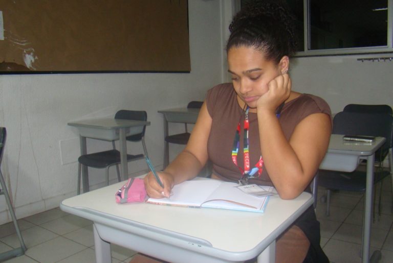 Ana Luisa, com os seus três crachás, faz anotações em sala do Pecep: estudo como instrumento para transformar a realidade (Foto: Lara Dominato)
