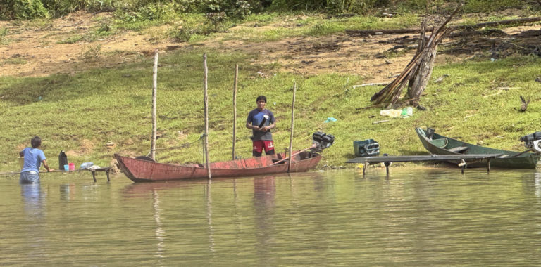 Foto colorida de pessoa em barco nas margens de Rio na região de Jacareacanga (PA)
